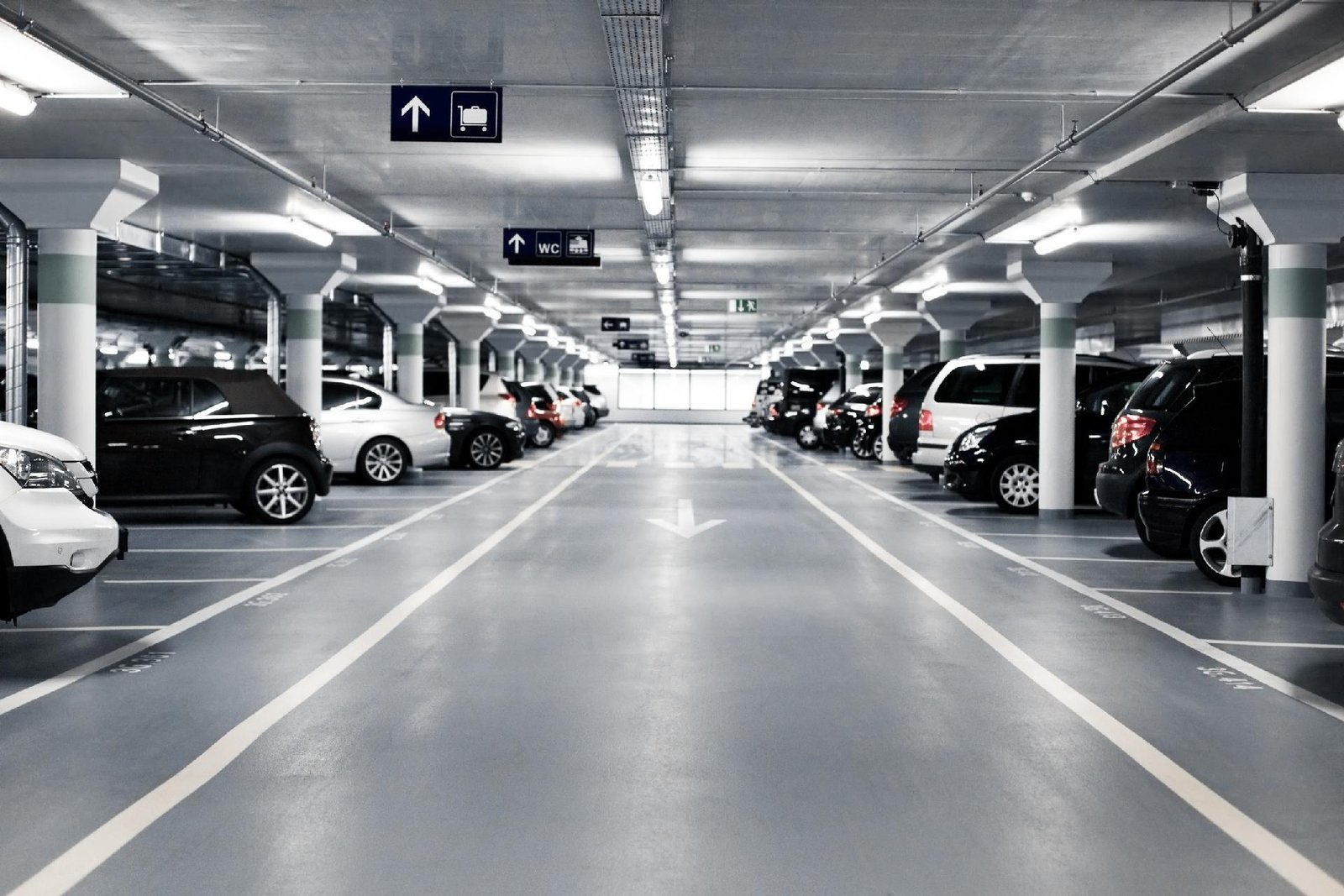 Amplio parking techado en aeropuerto con coches estacionados